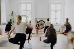 Gruppe von Personen beim Yoga in einem Raum mit Fenstern
