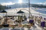 Sonnige Winterszene mit Skipisten und Sitzbereich im Freien
