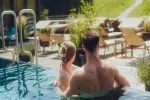 Paar im Pool mit Liegestühlen im Hintergrund