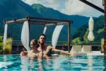 Paar im Pool mit Berglandschaft im Hintergrund