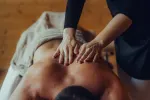 Eine Person erhält eine Massage mit Händen auf dem Rücken.
