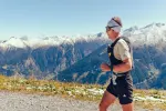 Läufer auf einem Bergweg mit schneebedeckten Gipfeln