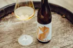 Eine Weinflasche und ein Glas auf einem Holzfass.