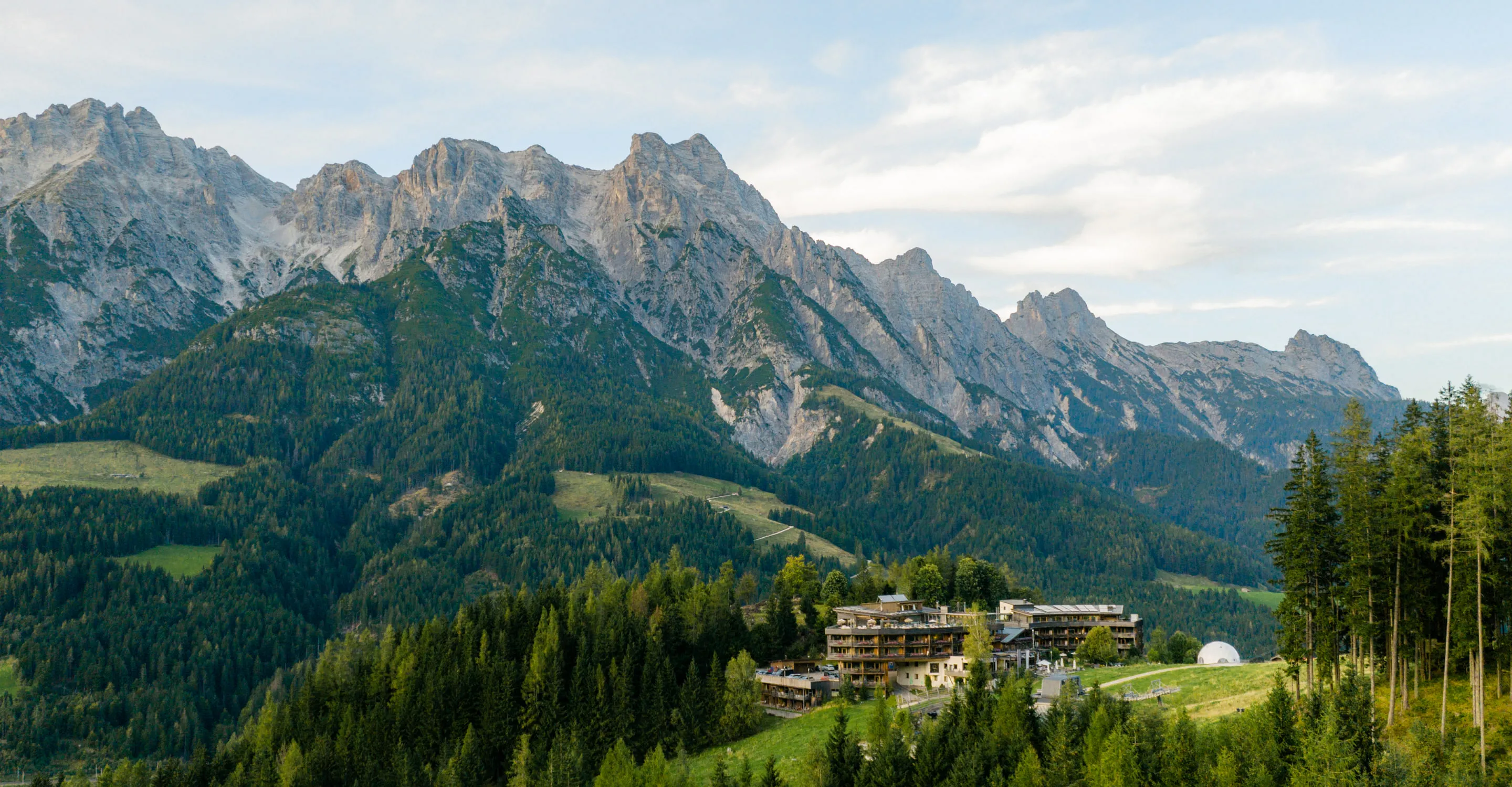 Berglandschaft mit Bäumen und einem Hotel