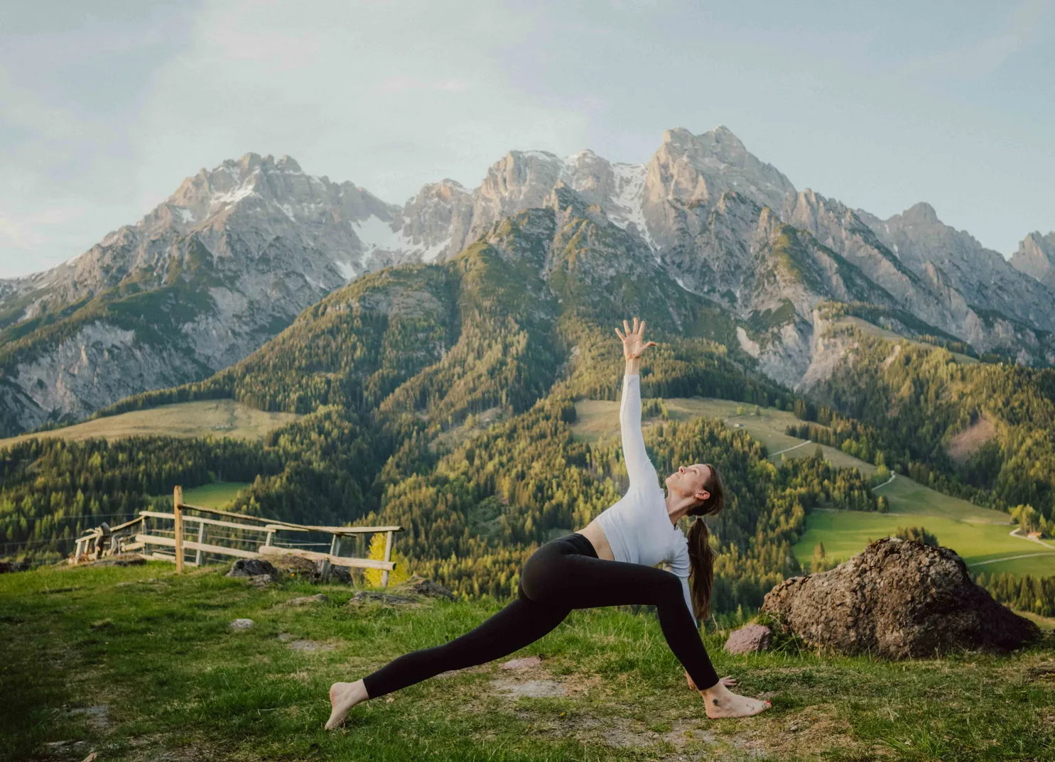 Yogaübung in den Bergen, grüne Wiesen und Felsen im Hintergrund
