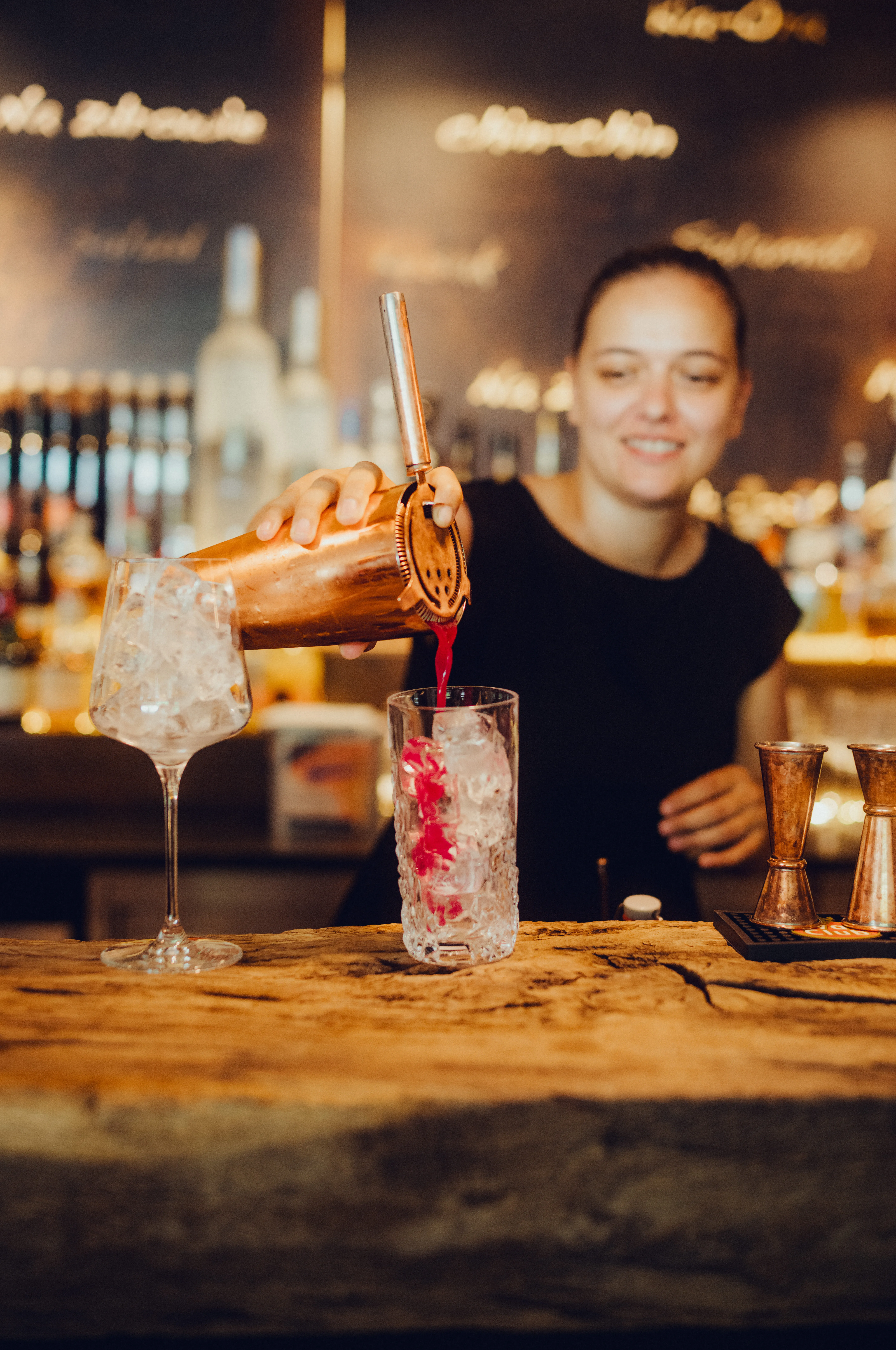 Barkeeperin schüttet Cocktail ins Glas