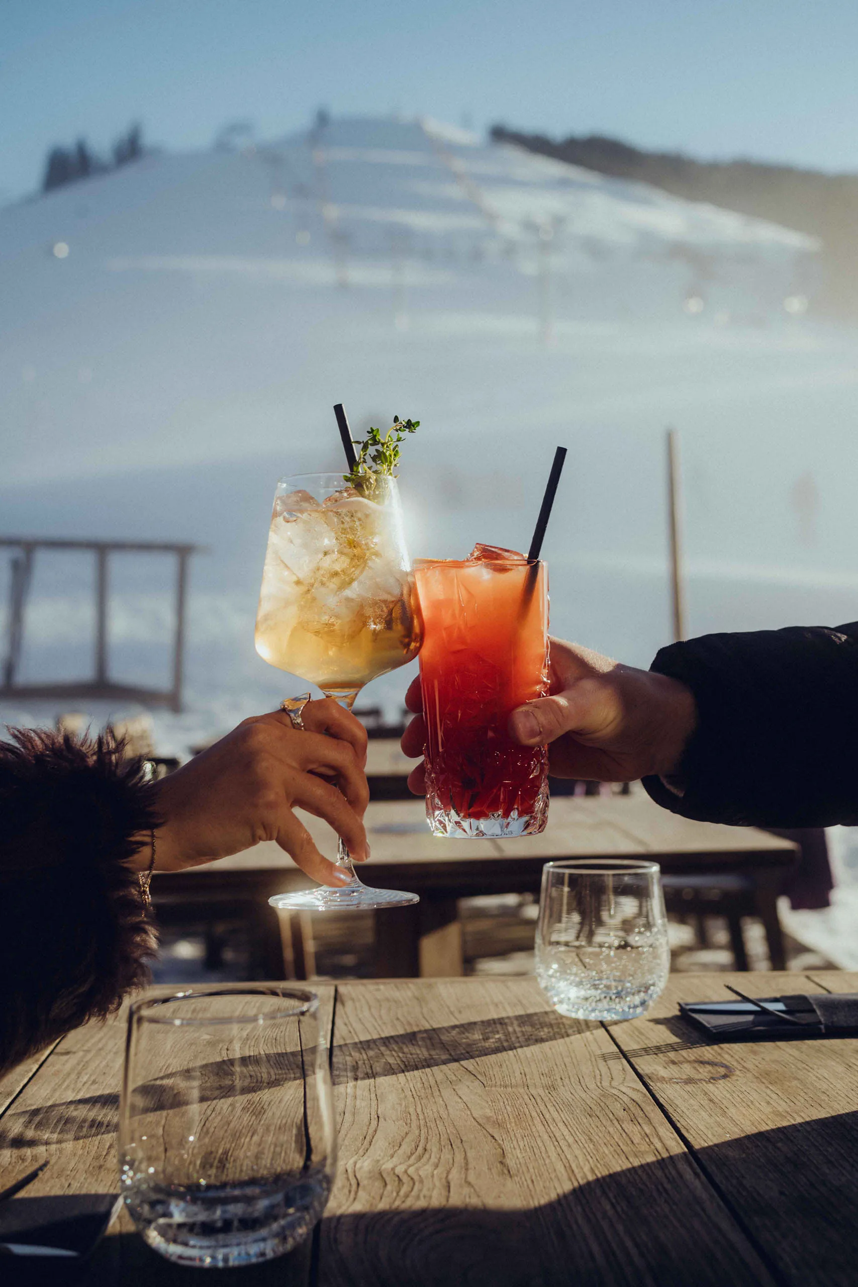 Menschen stoßen mit Cocktails an auf der Sonnenterrasse