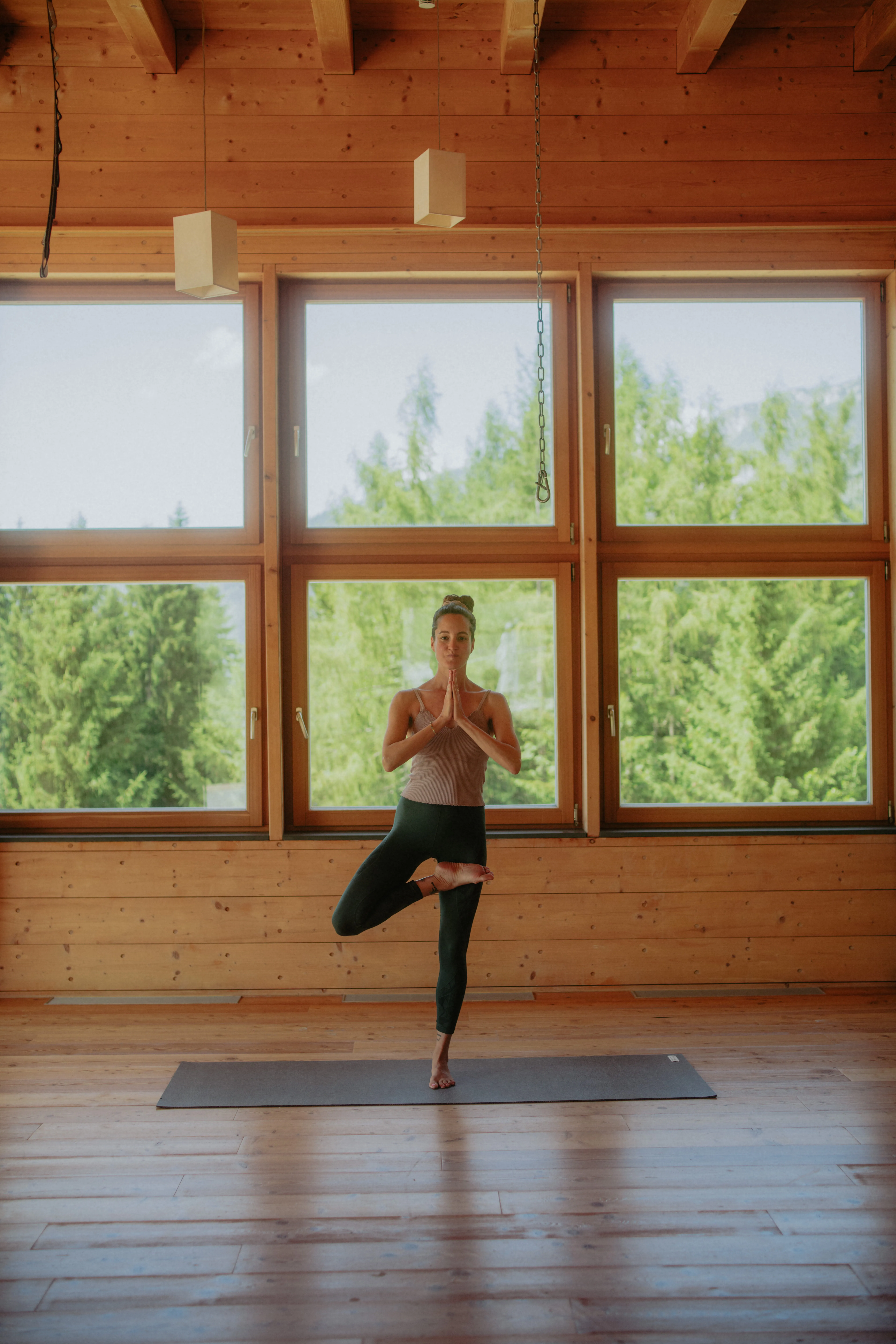 Frau praktiziert Yoga im Yogaraum aus Holz