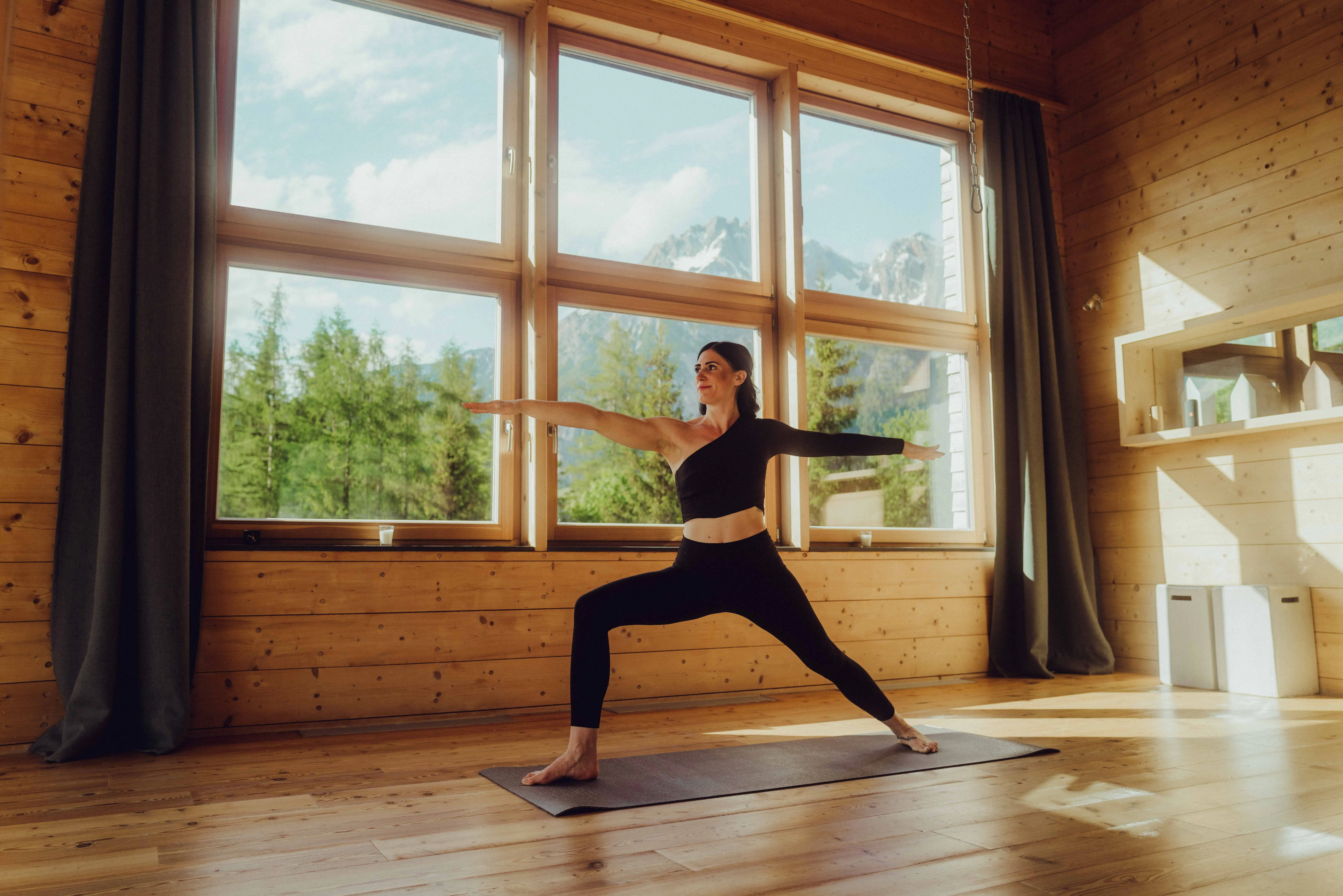 Frau praktiziert Yoga im Yogaraum aus Holz