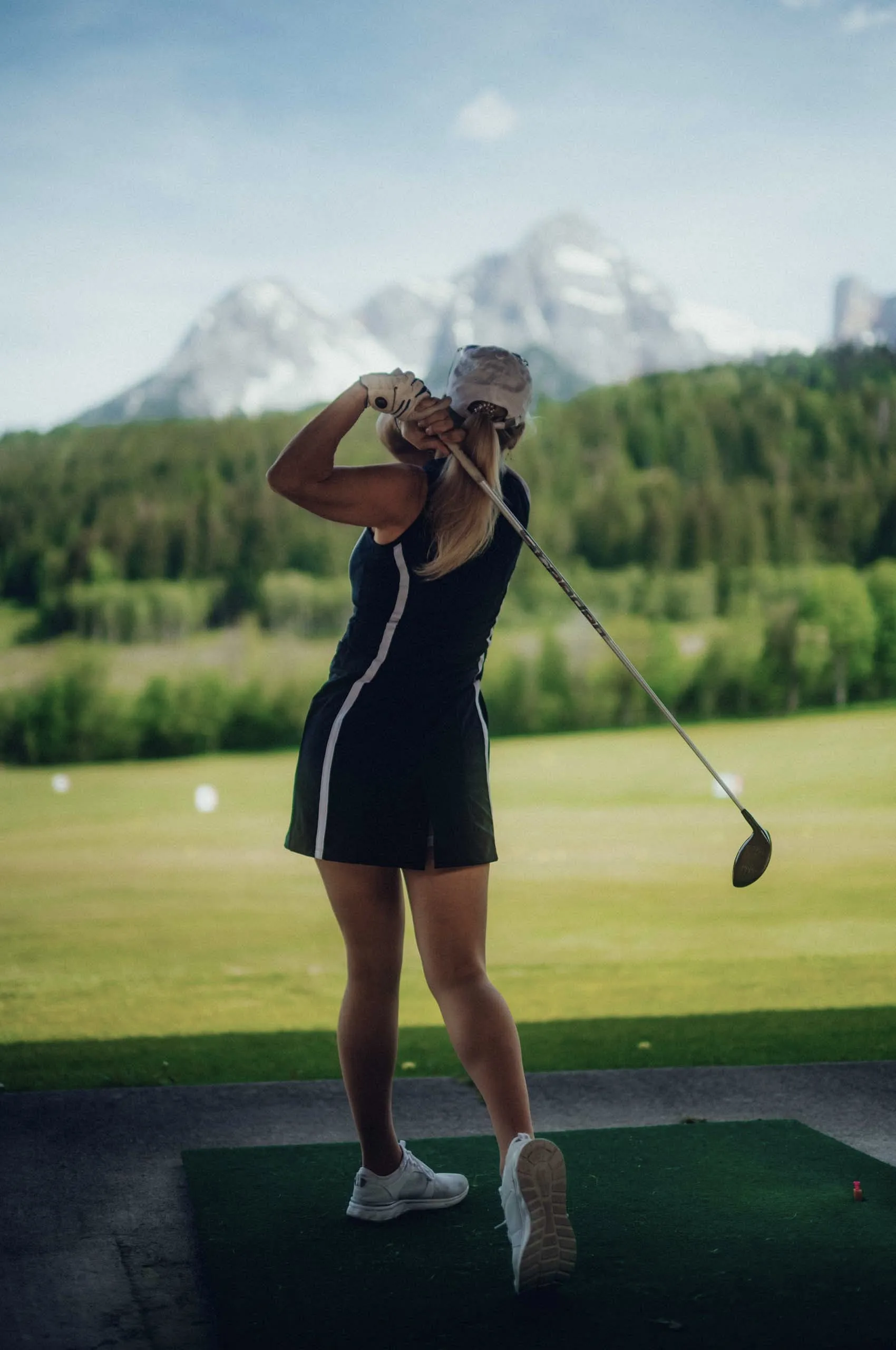 Frau spielt Golf vor Bergkulisse