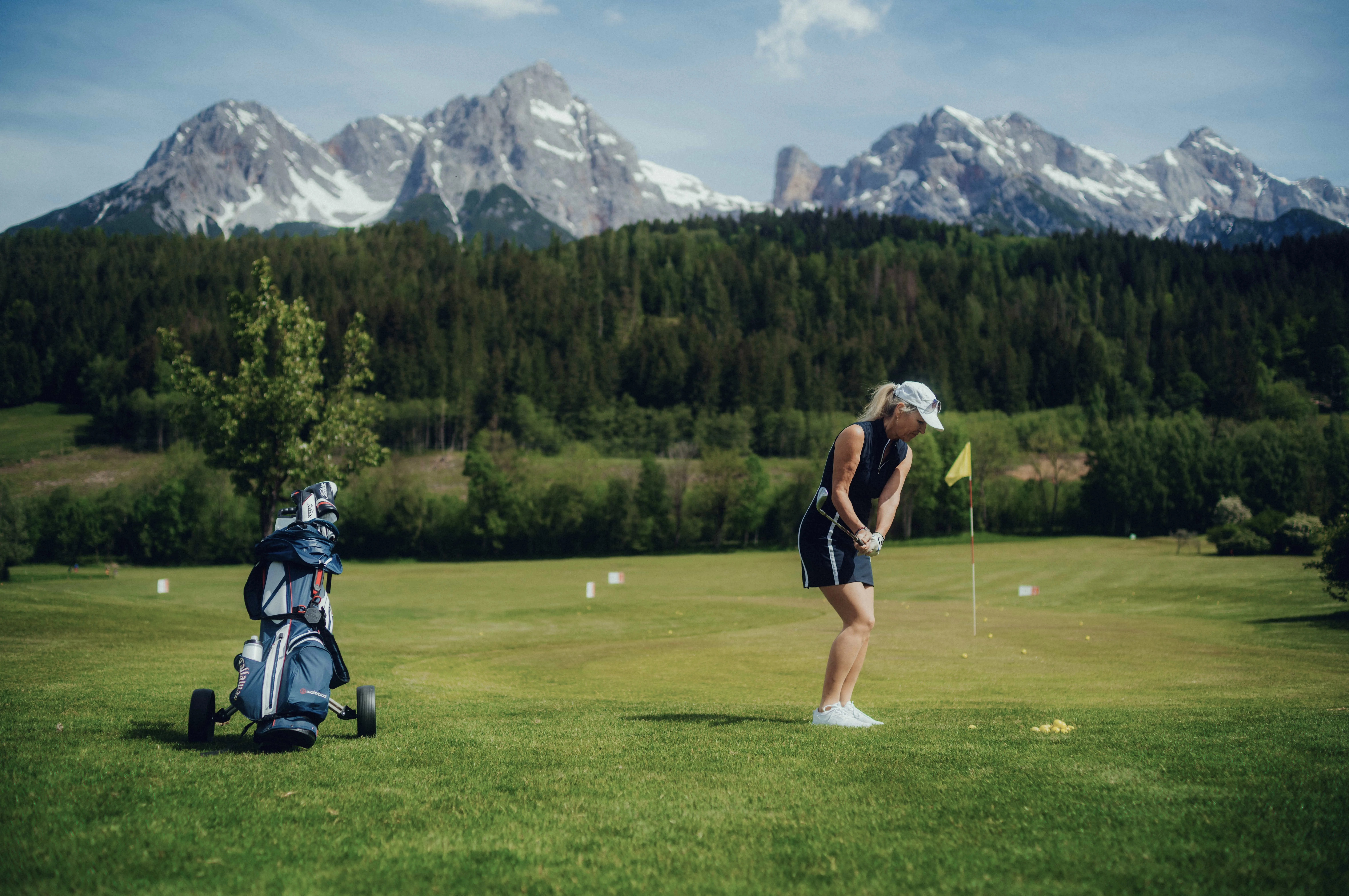 Frau spielt Golf vor Bergpanorama