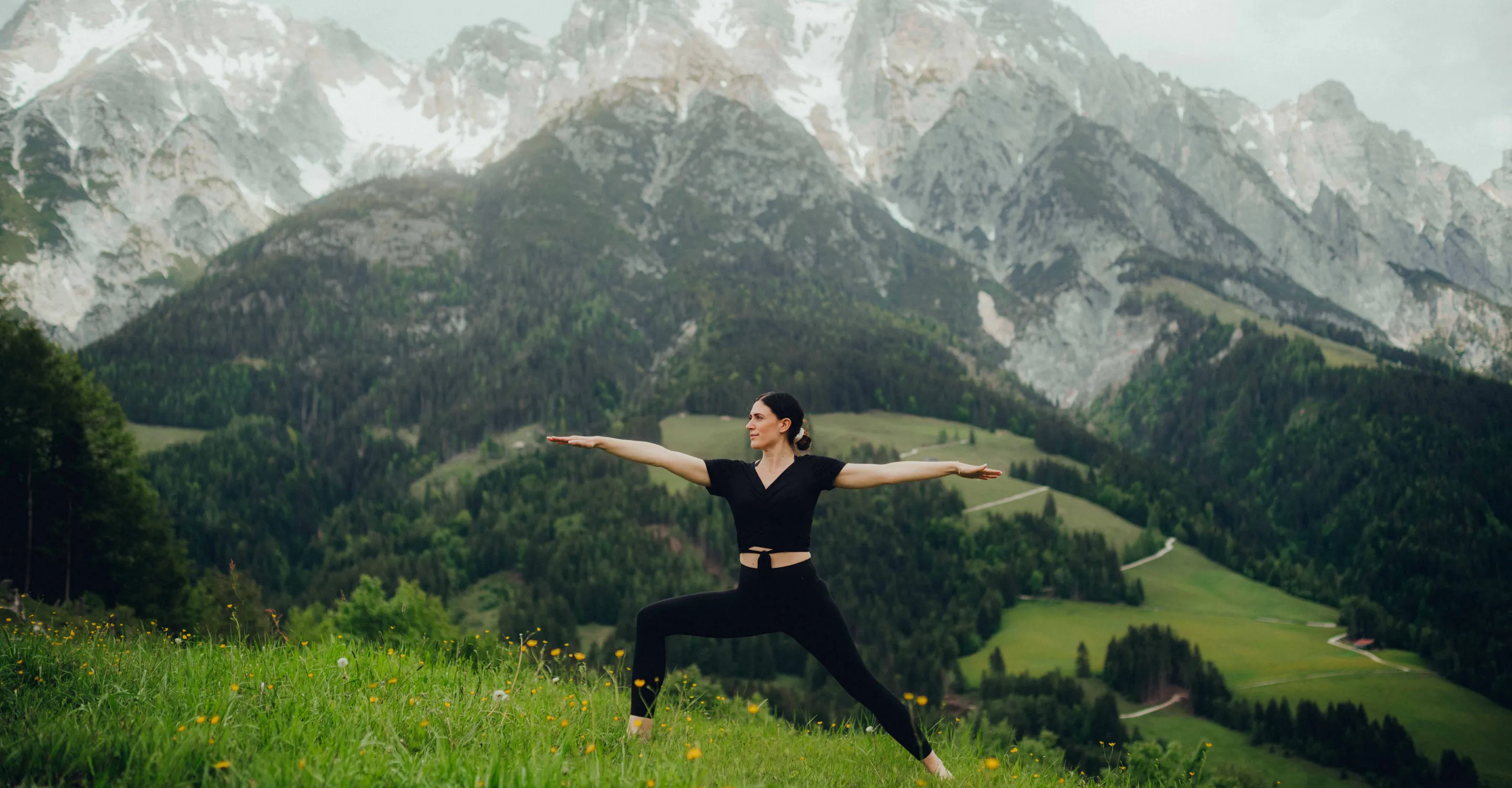 Frau in Yoga-Pose vor bergiger Landschaft
