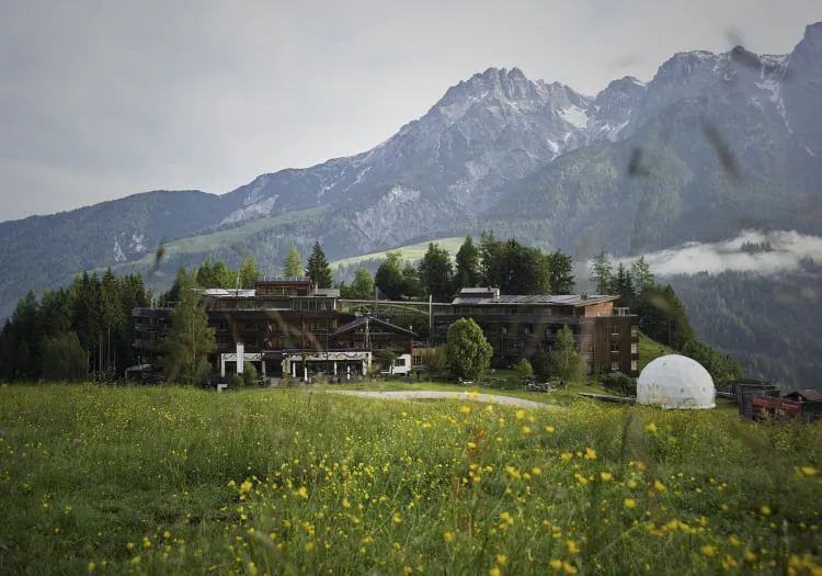 Holzhotel Forsthofalm in Leogang, umgeben von Bergen und Wiese