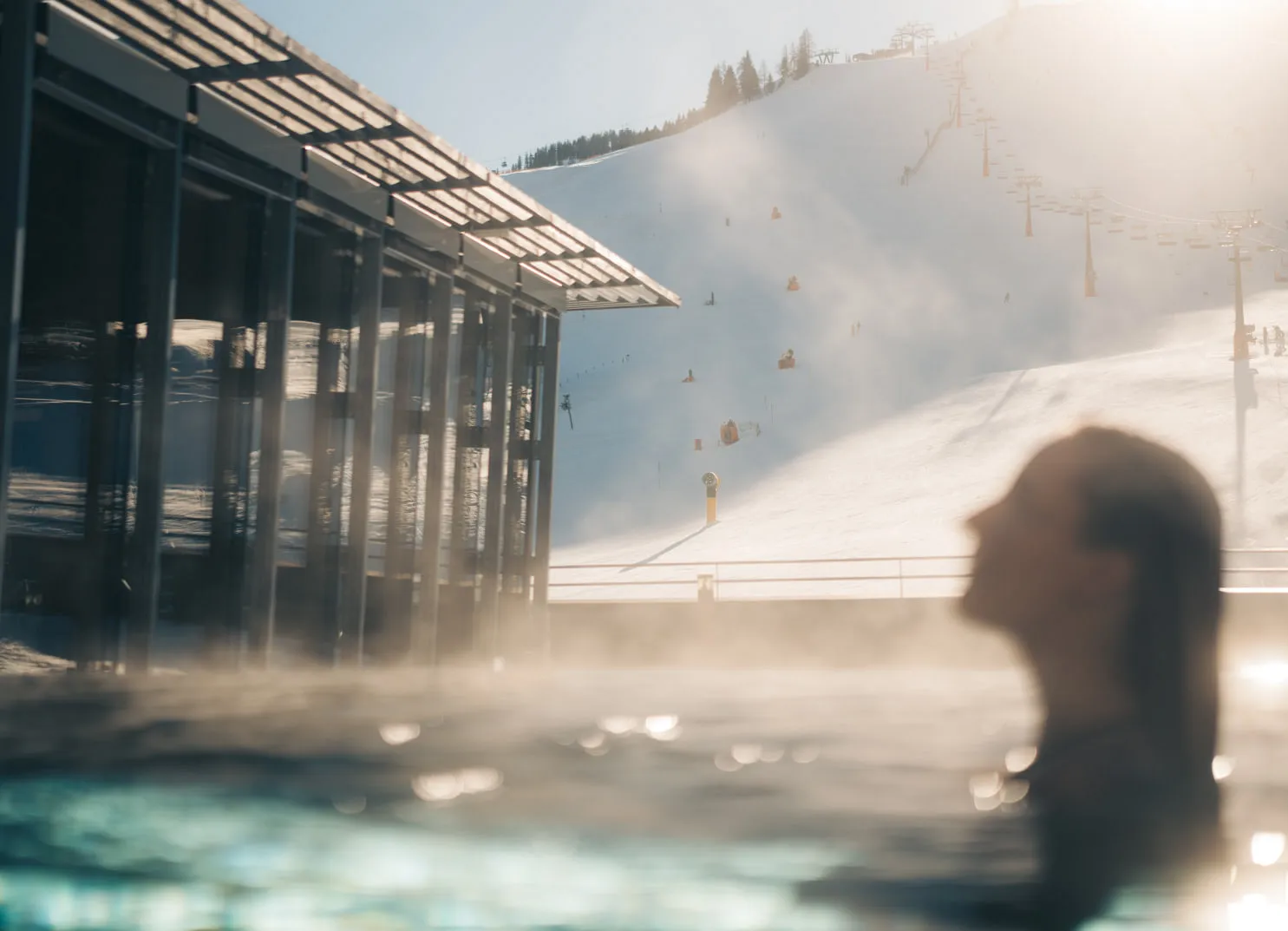 Blick auf das Holzhotel Forsthofalm in Leogang mit Schwimmbad und Skipiste