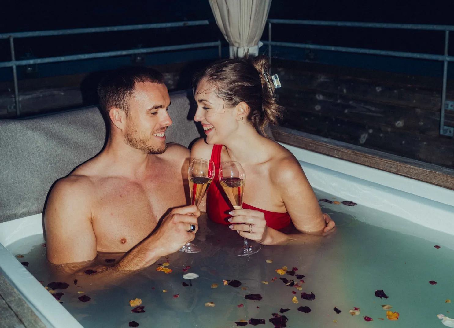 Paar entspannt in einem romantischen Bad am Abend mit Cocktails.