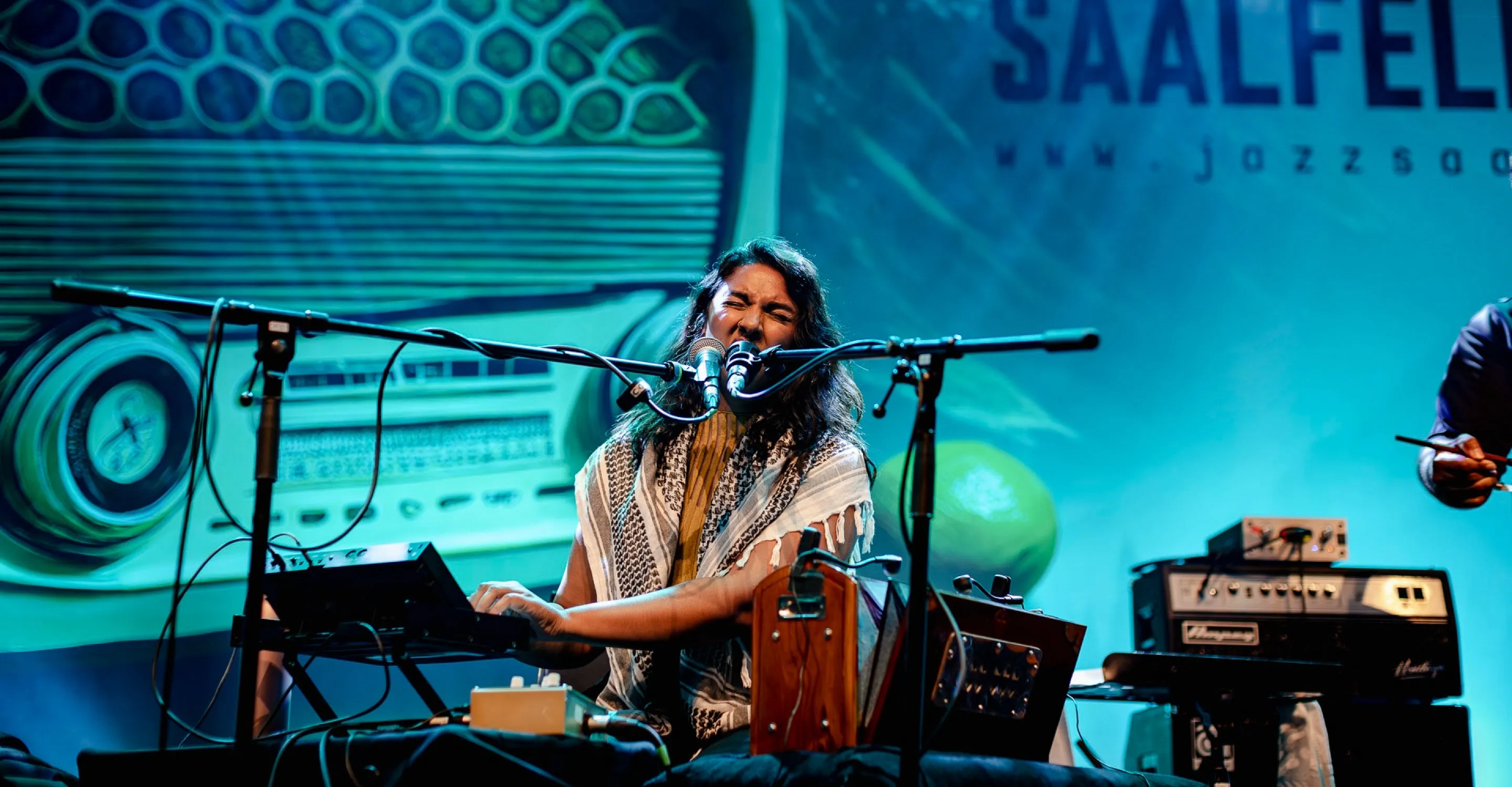Frau spielt auf der Mainstage mit Instrumenten und Mikrofons, Bühnenhintergrund