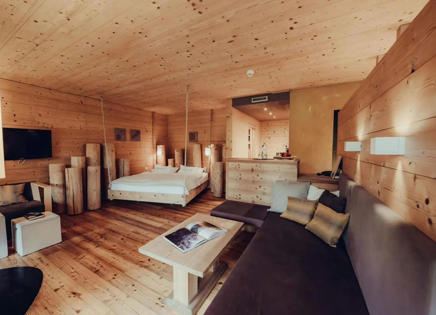 Holzgetäfeltes Zimmer mit Bett, Sofa und Holzsäulen