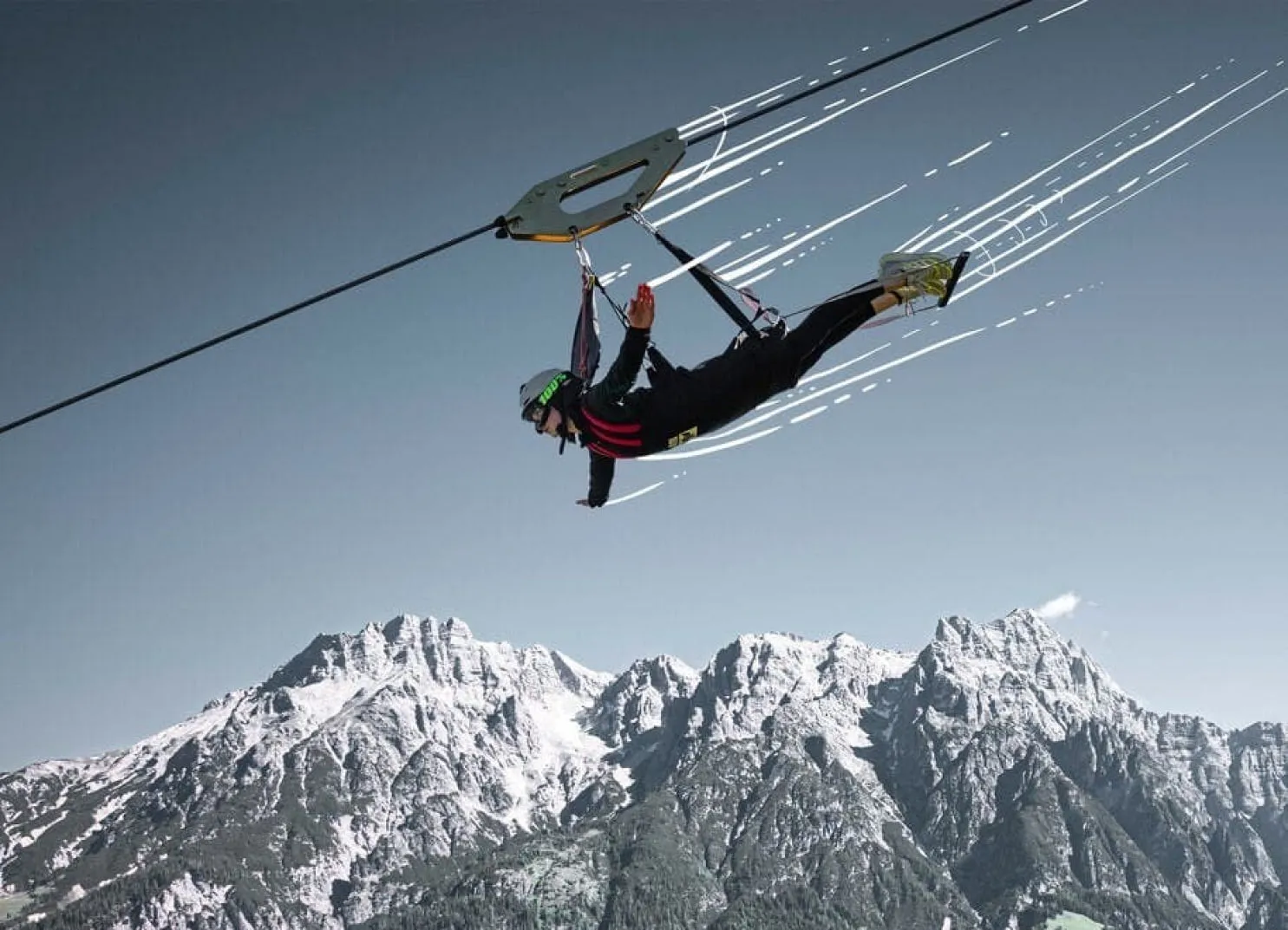 Person schwingt an einer Zipline über schneebedeckte Berge