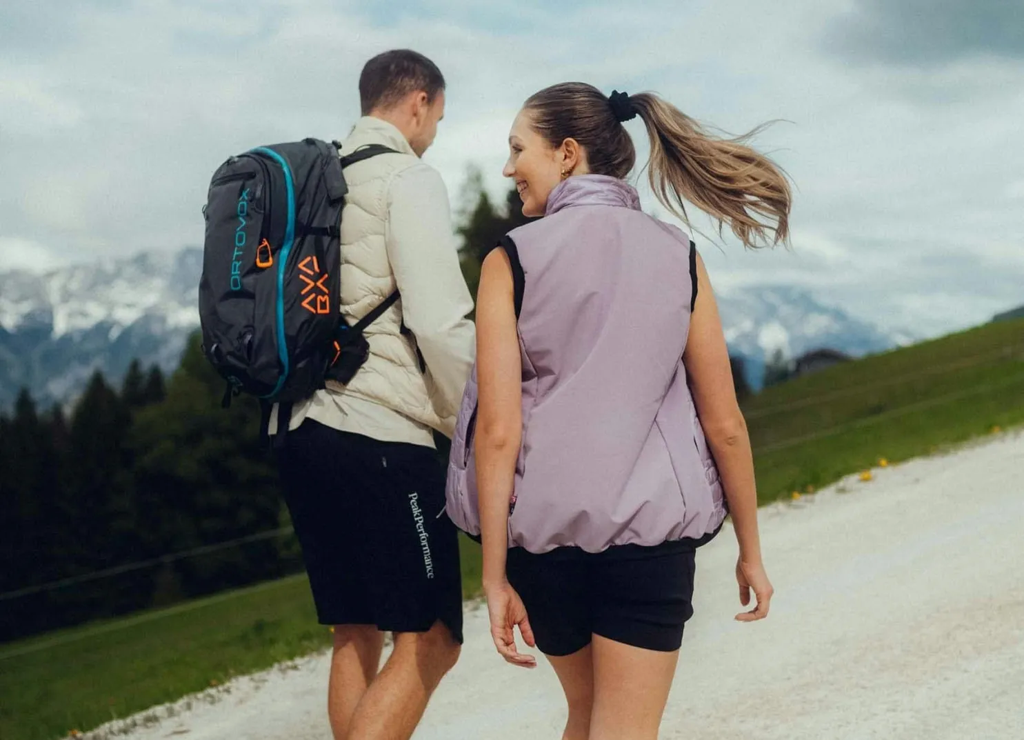 Zwei Personen beim Wandern mit Rucksack in der Natur, Berge im Hintergrund