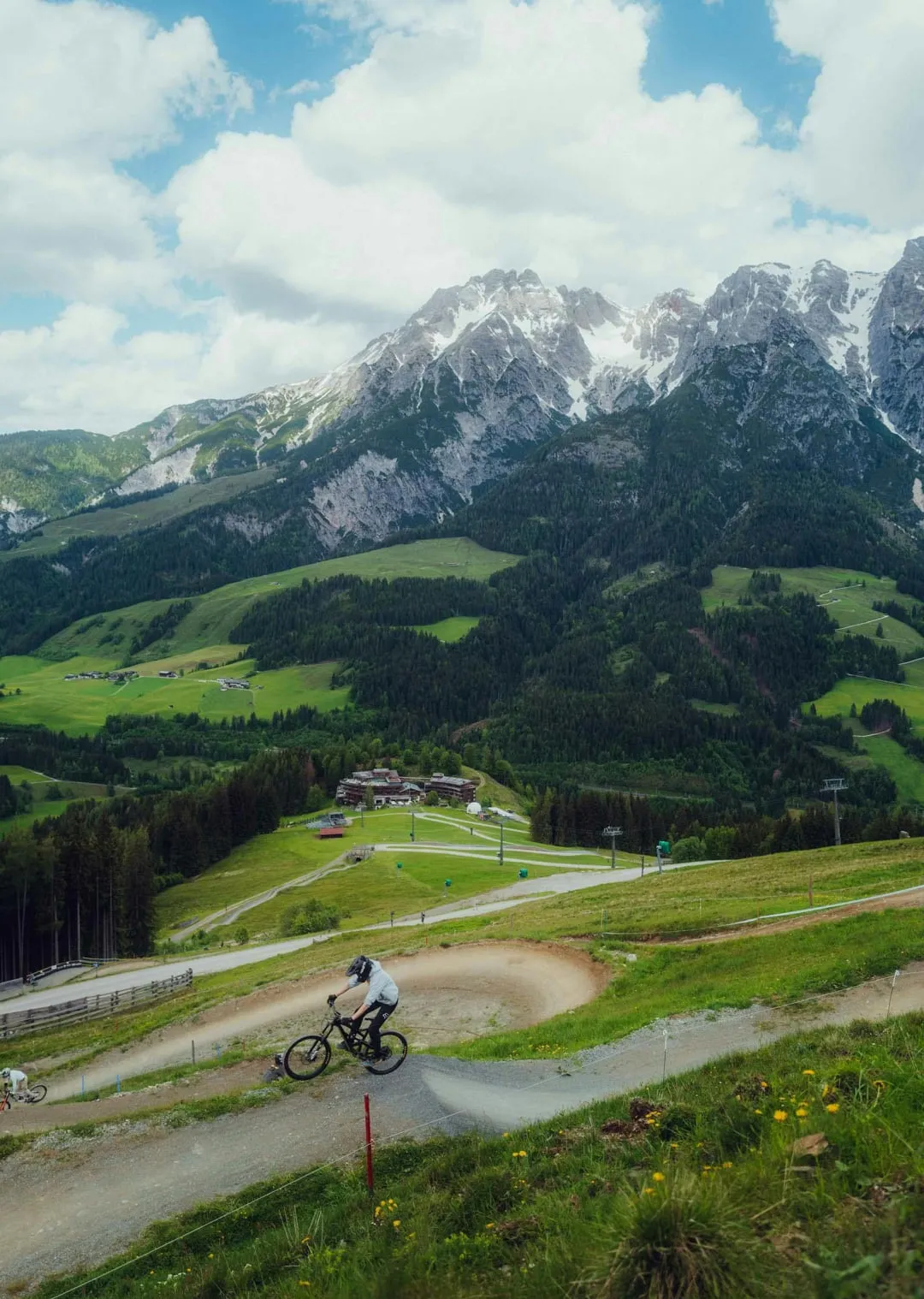 Mountainbiker auf einem erdigen Weg mit Bergen im Hintergrund
