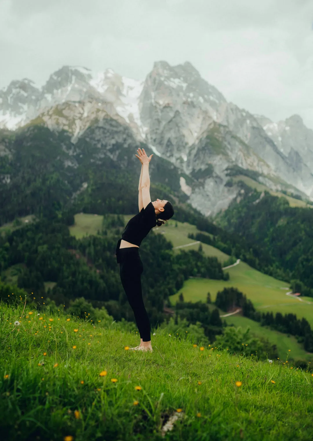 Person dehnt sich mit erhobenen Armen in einer Berglandschaft