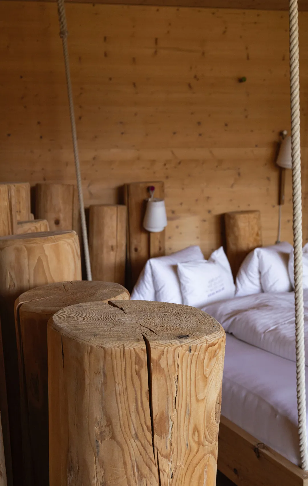Holzpfeiler in einem gemütlichen Holzraum mit Bett und Lampen