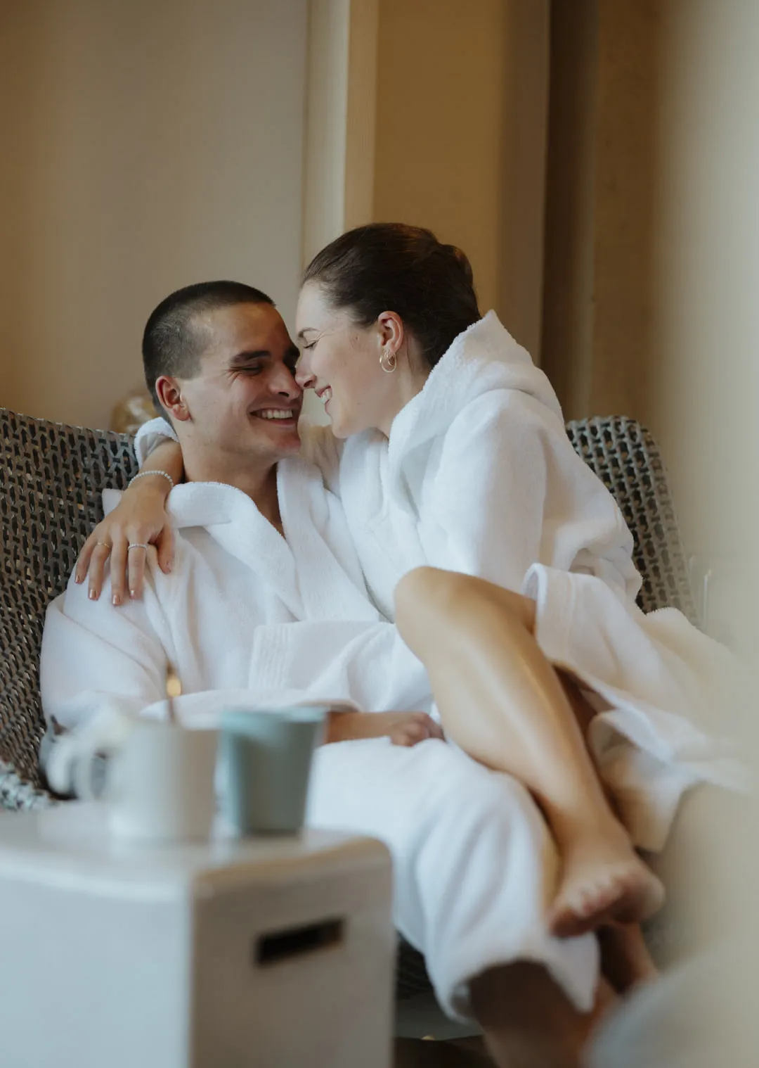 Paar in Bademänteln, entspannt und glücklich in einem Hotelzimmer.