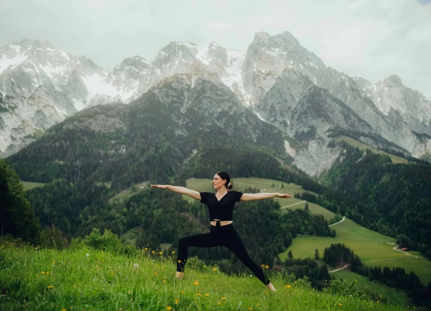 Frau in Sportkleidung macht Yoga-Posen vor Bergen