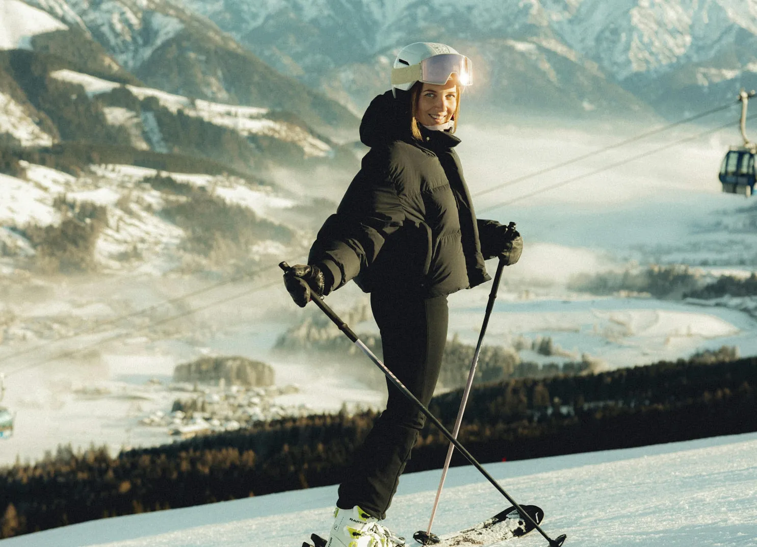 Skifahrer auf verschneiter Piste mit Bergen und Skilift im Hintergrund