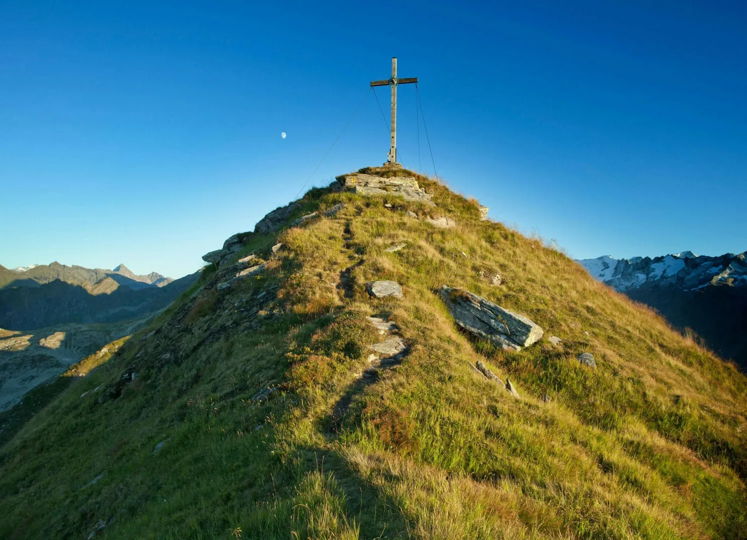 Berggipfel mit einem Kreuz vor klarem blauen Himmel