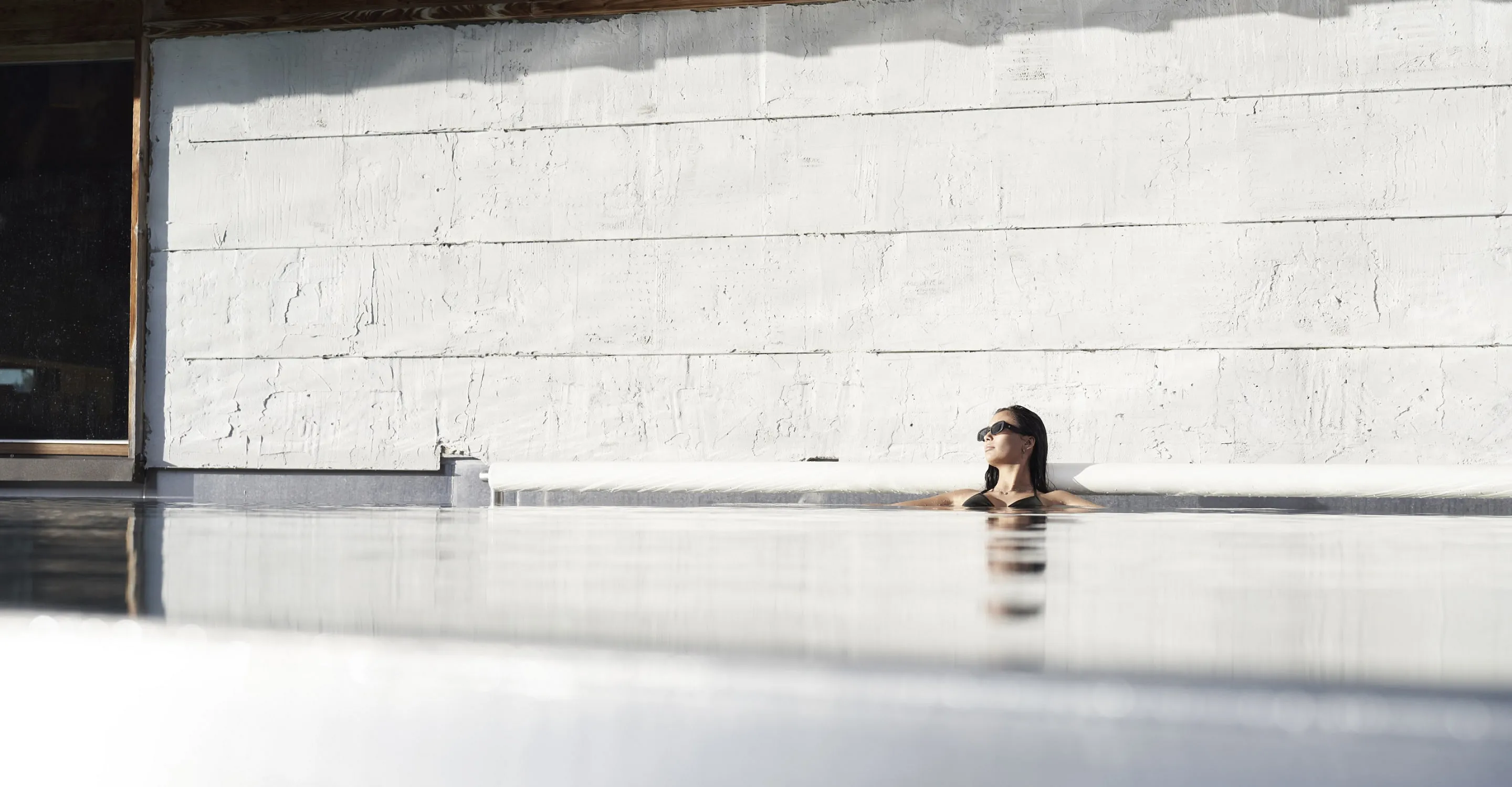 Frau entspannt im Pool des Holzhotels Forsthofalm in Leogang