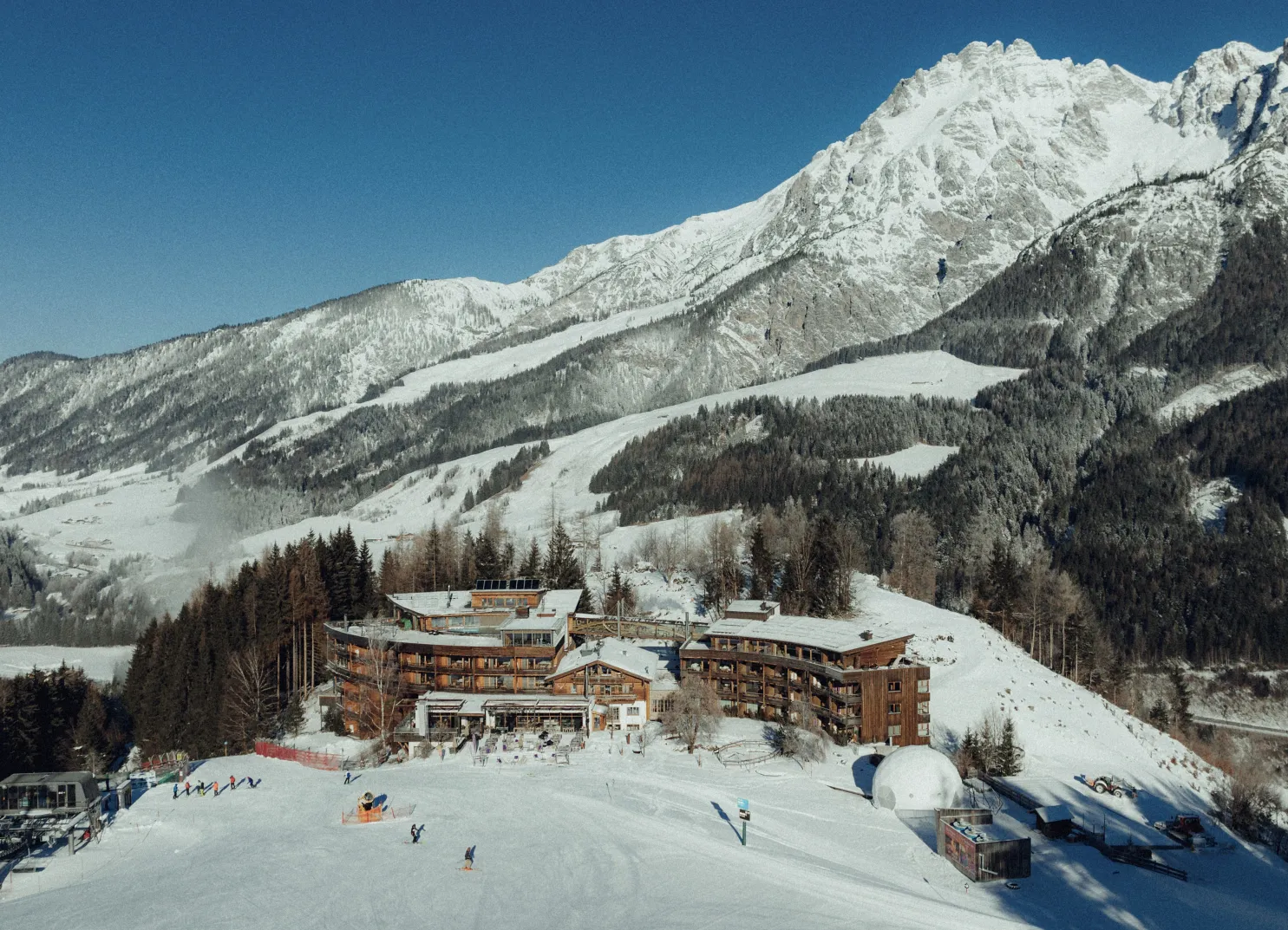 Holzhotel Forsthofalm in Leogang, umgeben von schneebedeckten Bergen