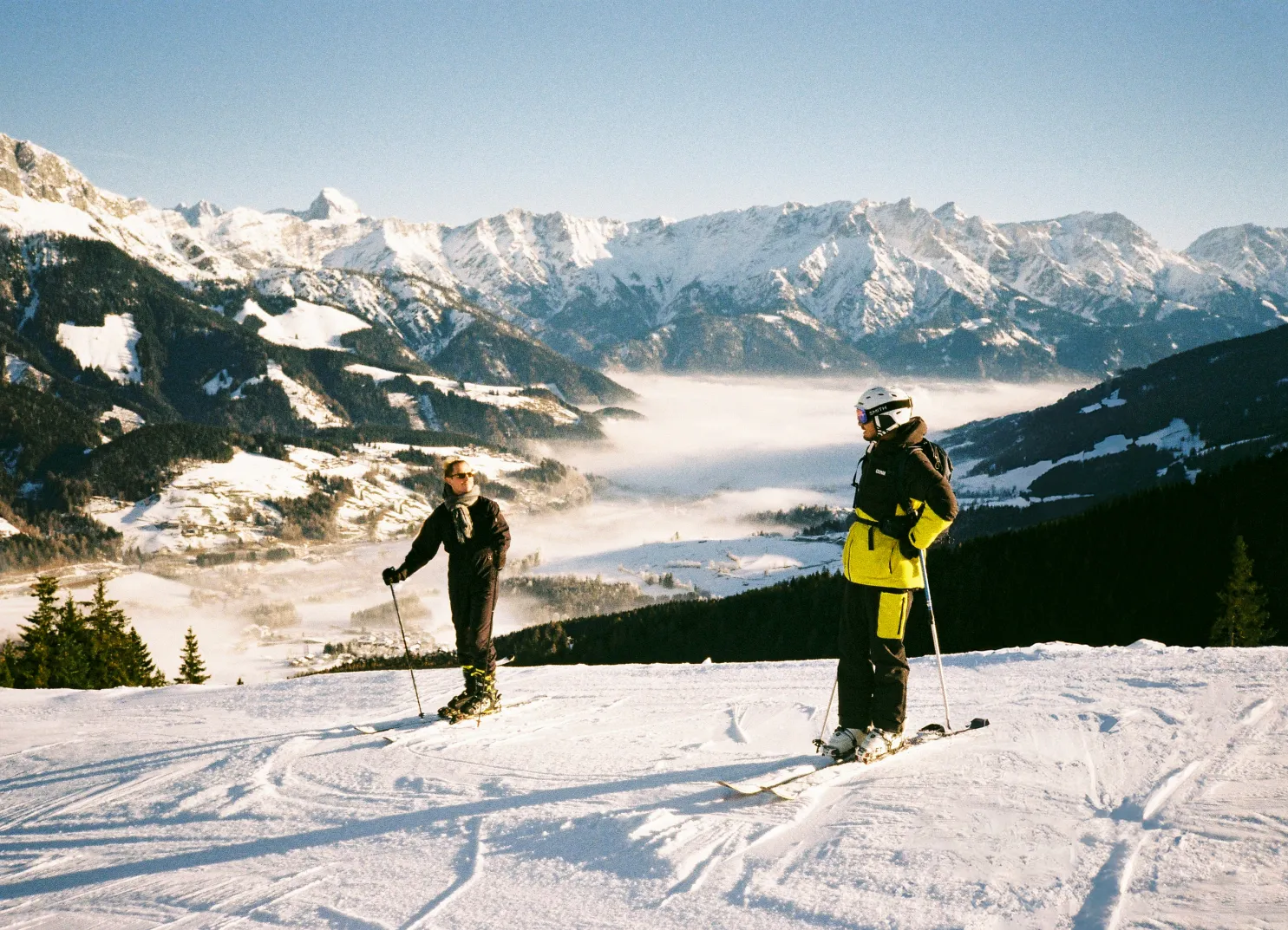 Zwei Skifahrer in Leogang, Winterlandschaft mit Bergen und Nebel im Tal