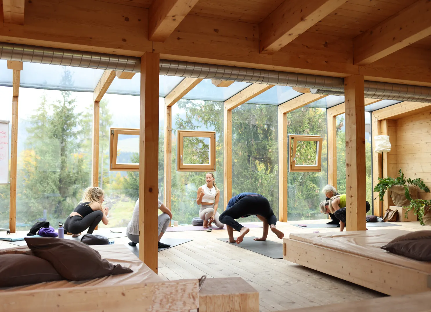 Yogaklasse in einem Holzraum mit großen Fenstern