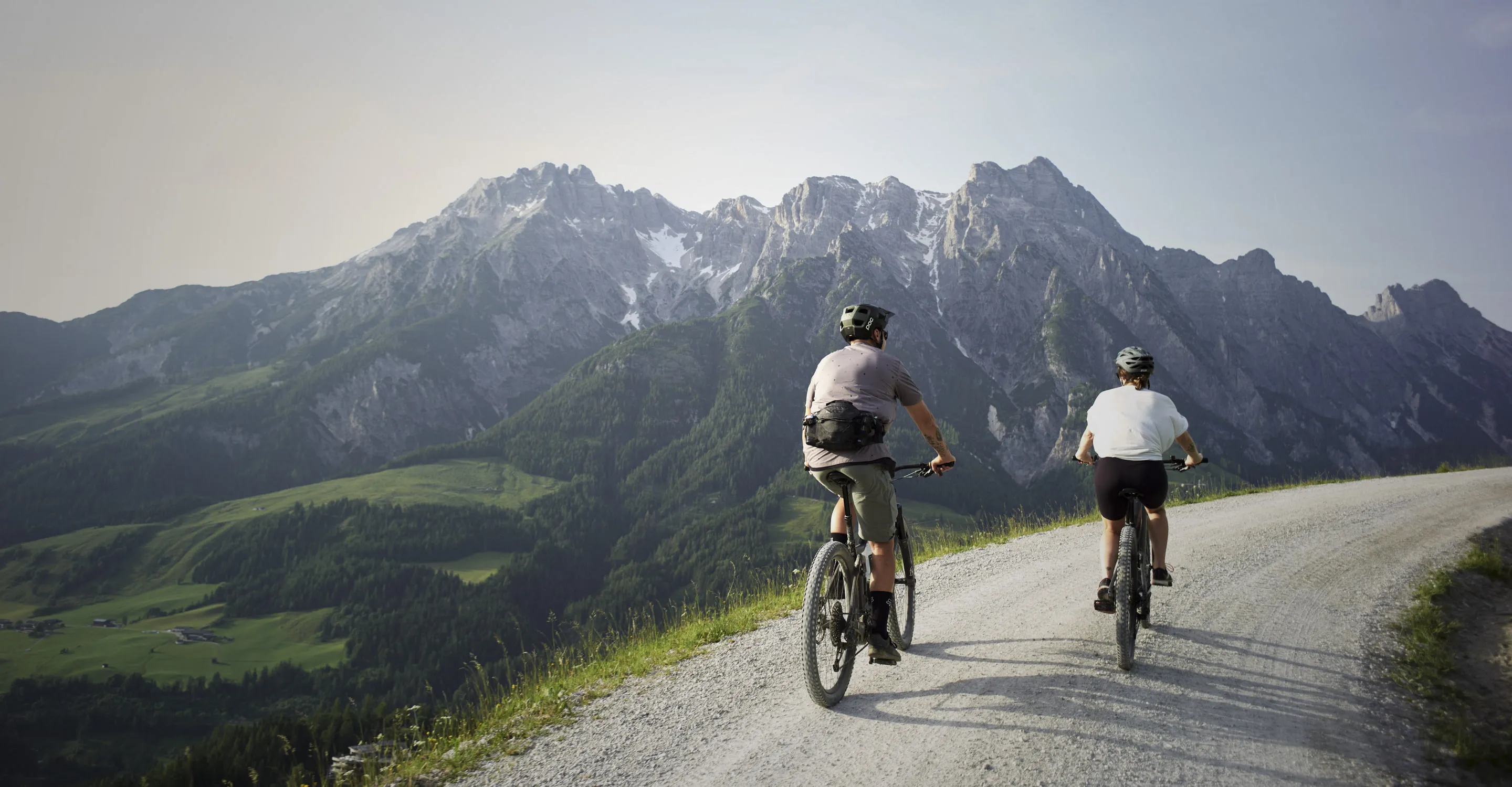 Zwei Radfahrer auf einem Schotterweg mit Bergen im Hintergrund