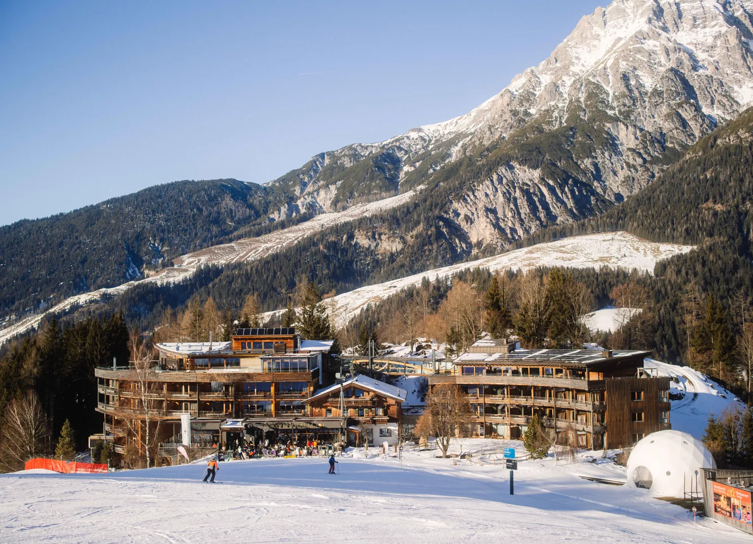 Hotel in den Alpen mit schneebedeckten Landschaft und Skipiste