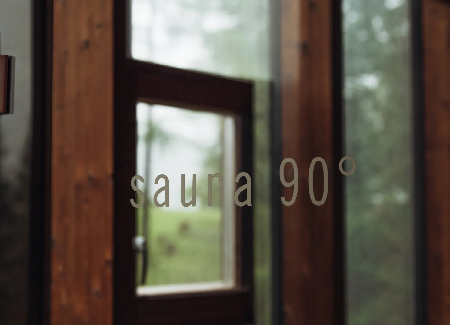 Holztür mit einem Fenster und der Aufschrift 'sauna 90°'