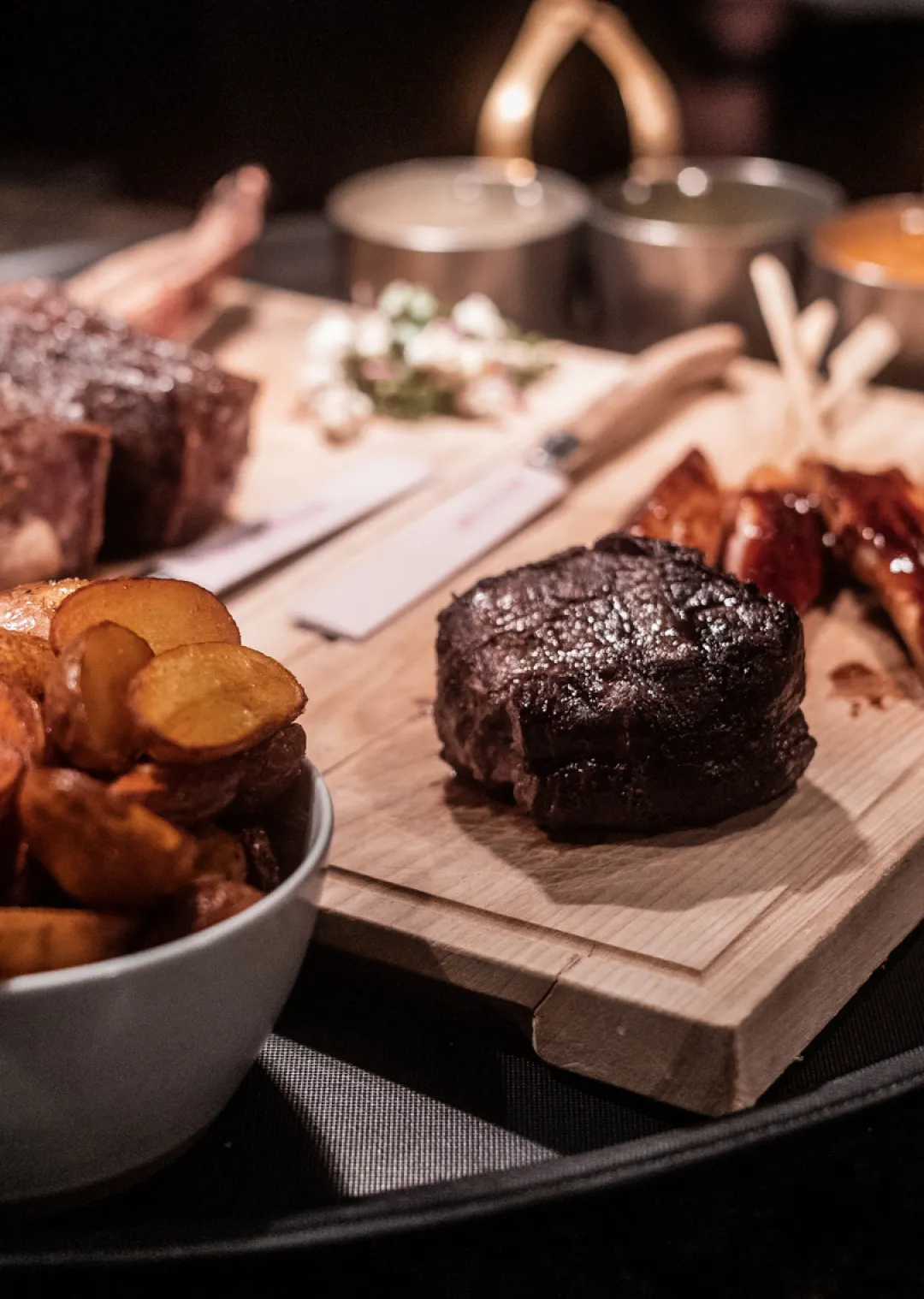 Platter with steak, potatoes, and sauces in a restaurant setting
