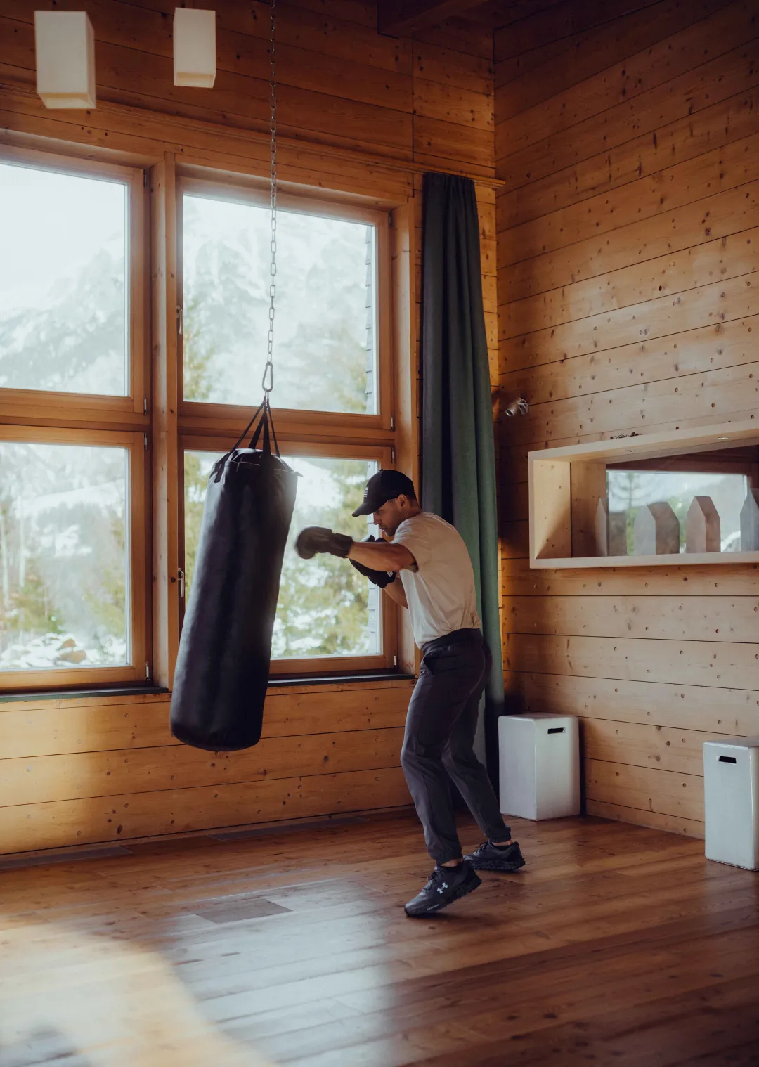 Mann trainiert an einem Boxsack im Holzhotel Forsthofalm