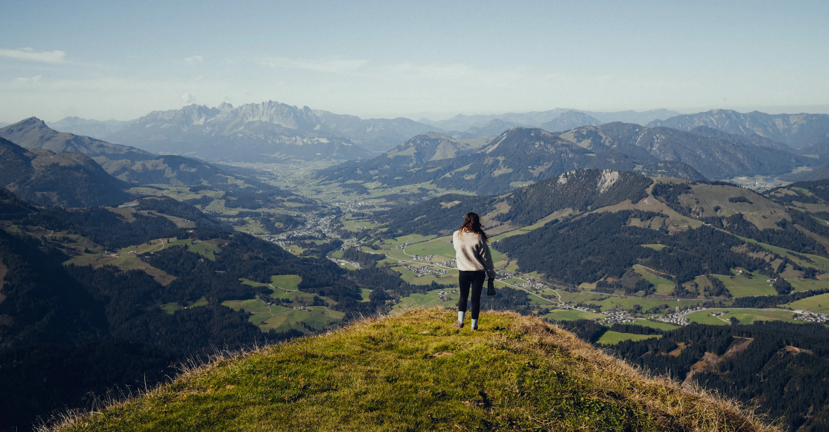 Person steht auf einem Gipfel mit Bergblick