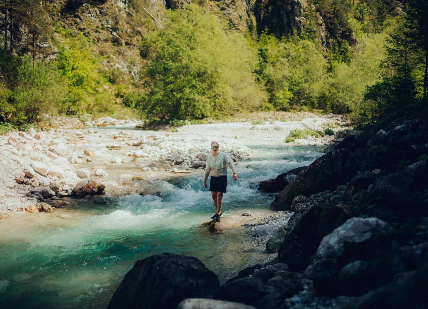 Person wandert über einen klaren Fluss in der Natur.