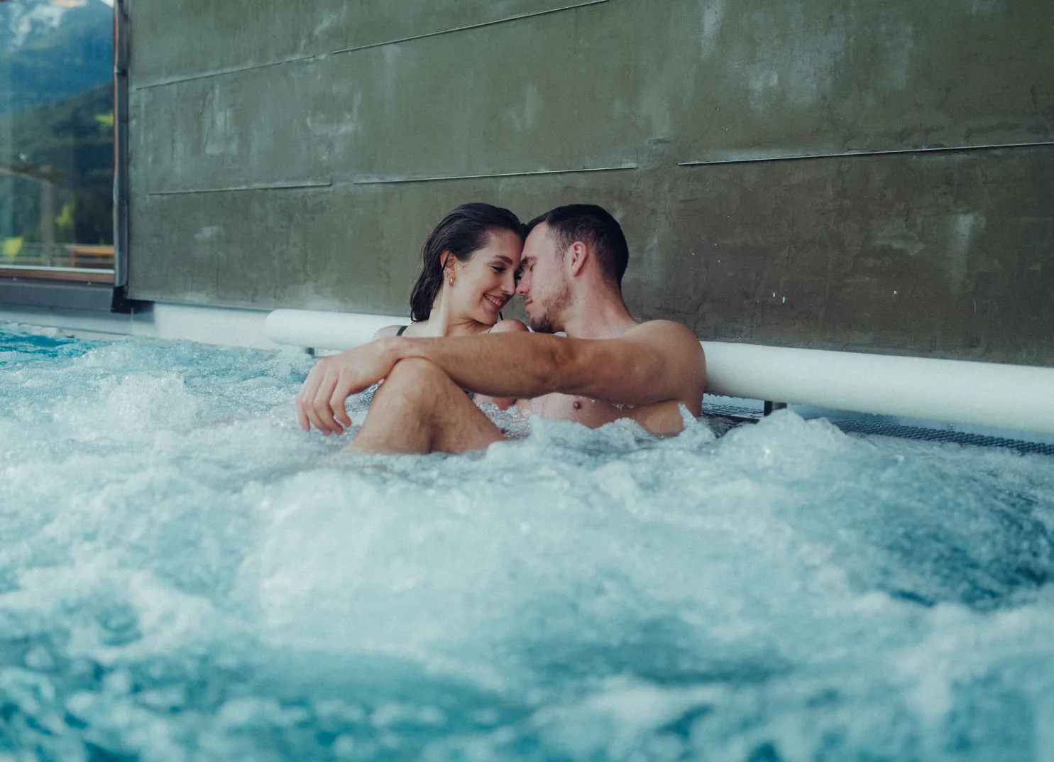 Paar entspannt im Pool, umgeben von Blasen und Wasser.