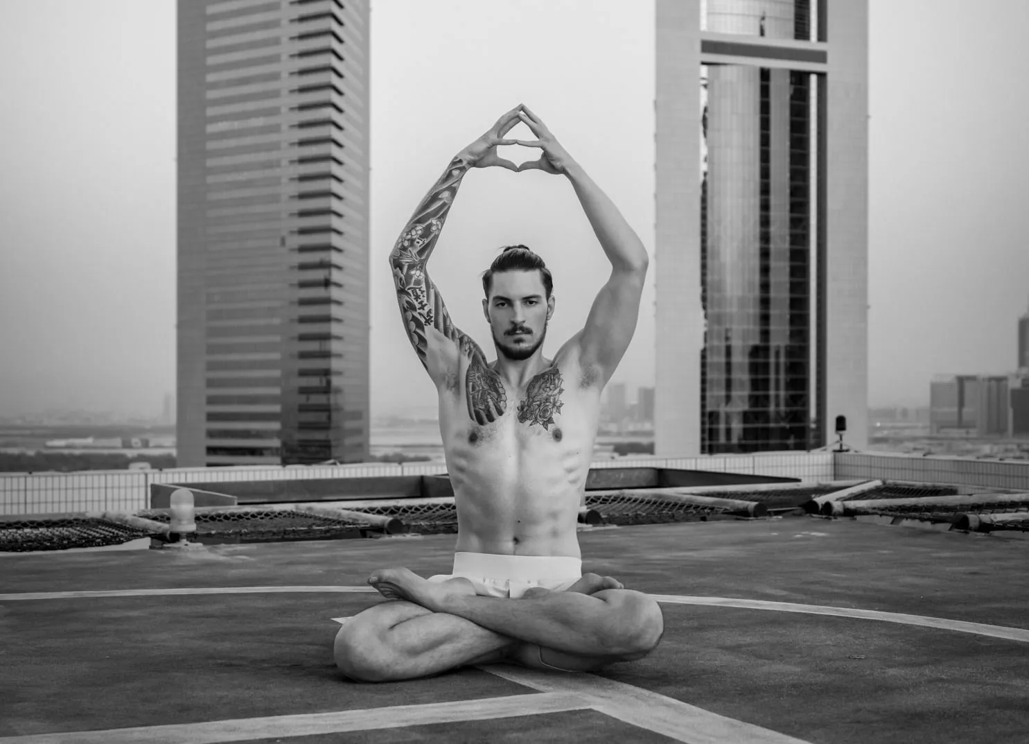 Mann praktiziert Yoga auf einem Dach mit Hochhäusern im Hintergrund