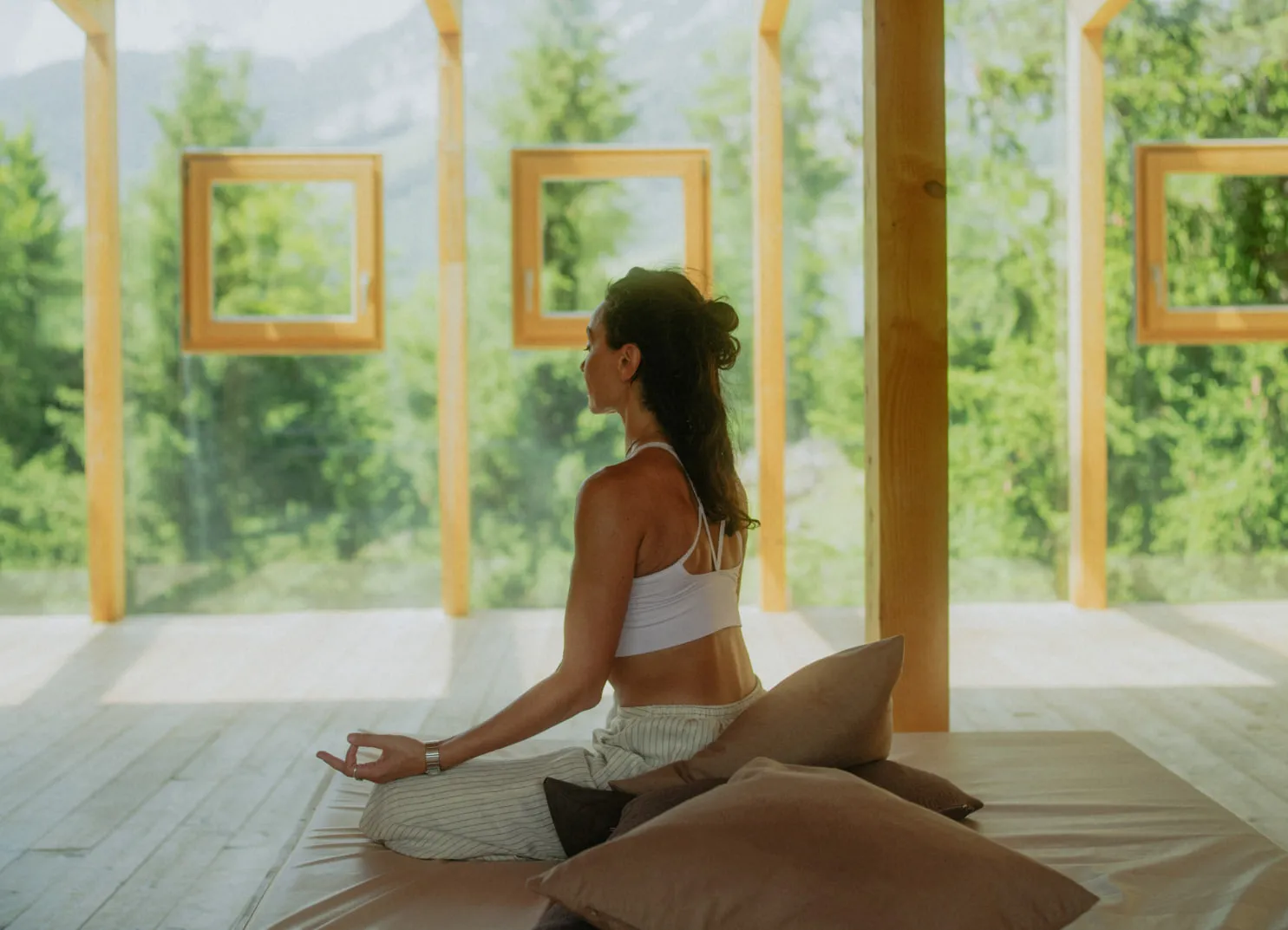 Frau sitzt in Meditation in einem ruhigen, naturnahen Raum