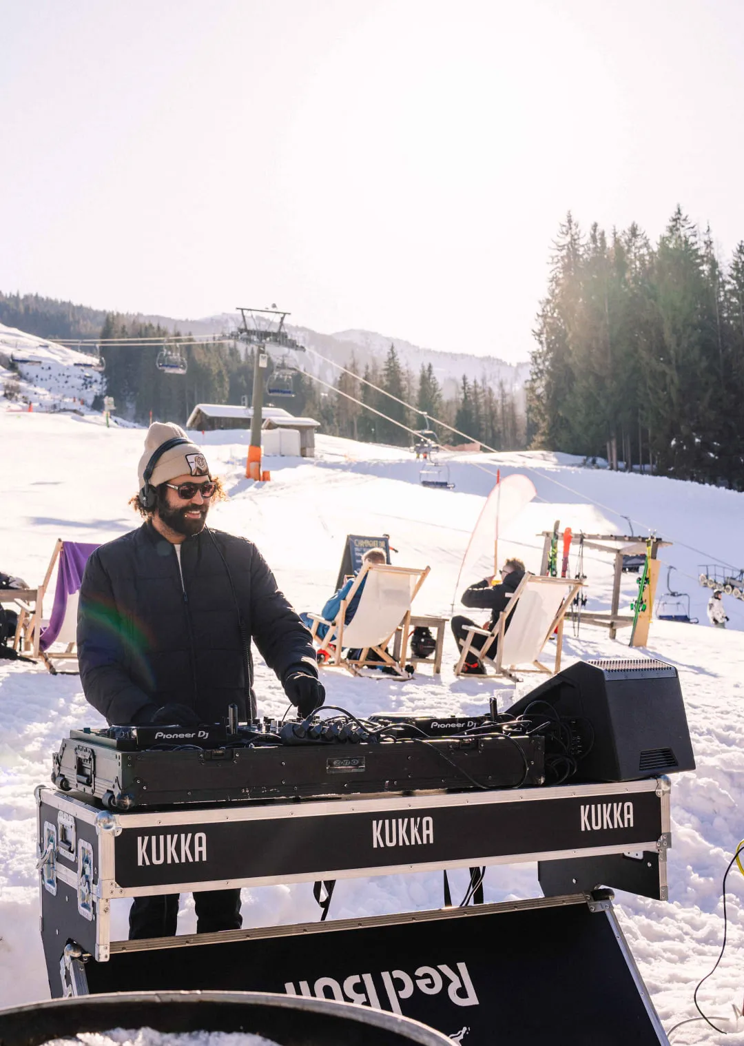 DJ at a booth in the snow with mountains in the background.