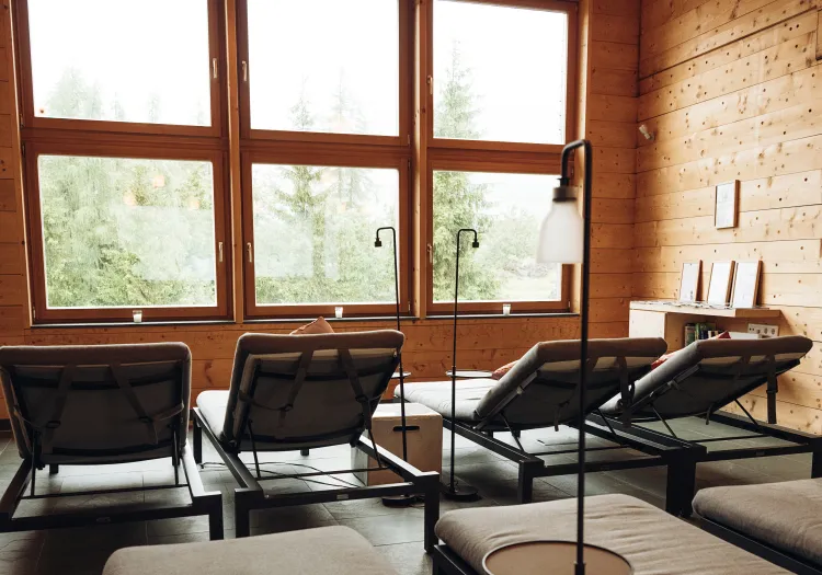 Lounge mit Liegen und Fenstern zum Wald