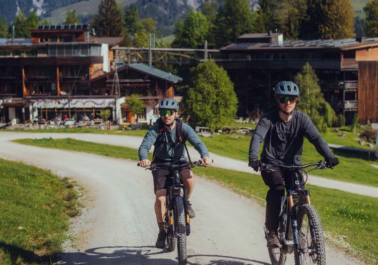 Zwei Radfahrer auf einem Weg mit einem Gebäude im Hintergrund
